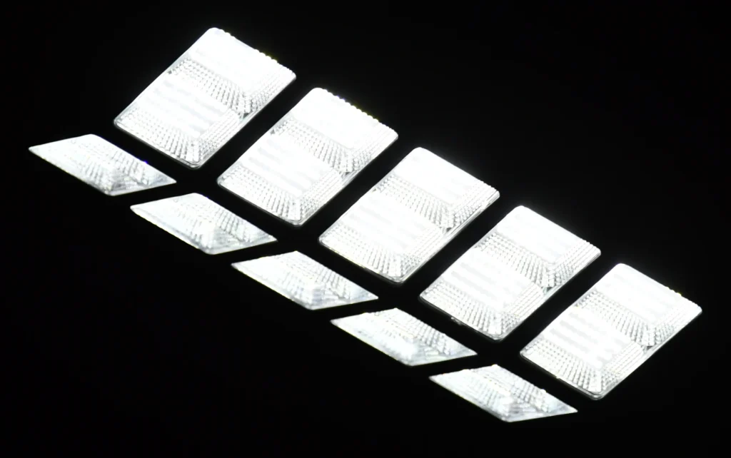 A row of six bright rectangular LED lights is arranged diagonally against a black background.